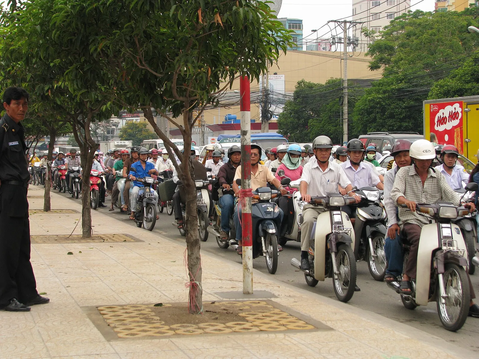 רוכבי קטנוע עם קסדות וכיסוי פנים בתנועה עמוסה ברחוב עירוני בווייטנאם
