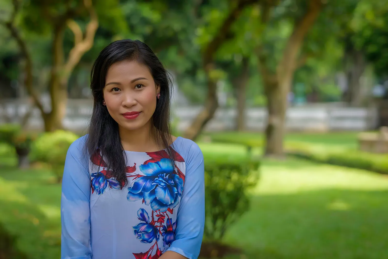 אישה לובשת אאו זאי, השמלה המסורתית התפורה של וייטנאם, בגן ירוק, מרכז וייטנאם