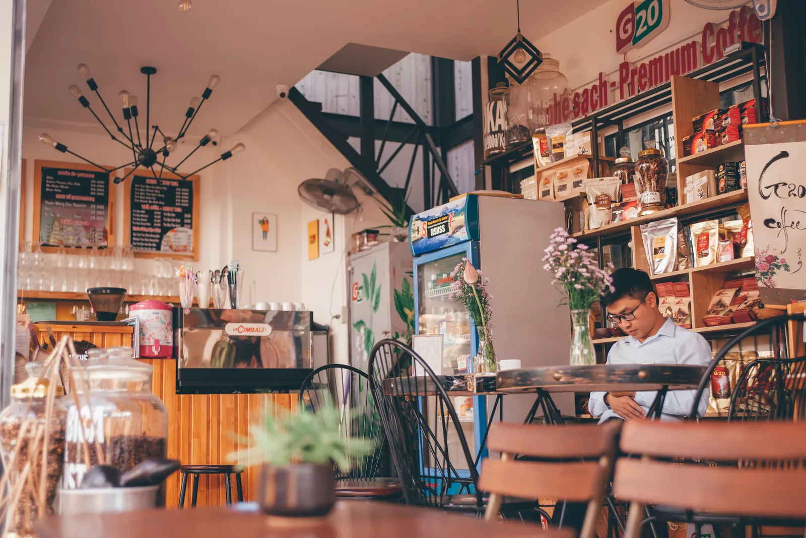 פנים בית קפה קטן בווייטנאם עם לוח תפריט כתוב ביד וקיר עמוס פריטי נוסטלגיה, אור יום